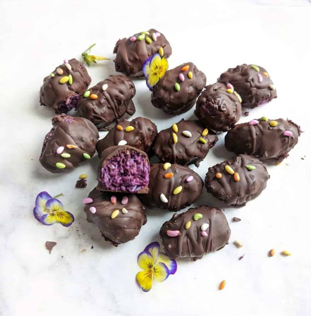 Chocolate Bounty Blueberry Bites wit one half eaten and decorated with edible flowers.