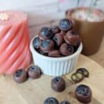 Frozen blueberries dipped in chocolate and creamy cashew nut butter. A pink candel in the background.