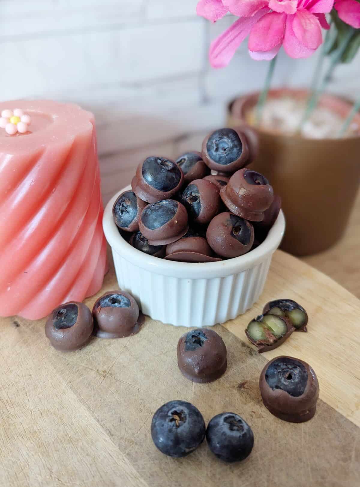 Frozen blueberries dipped in chocolate and creamy cashew nut butter. A pink candel in the background.