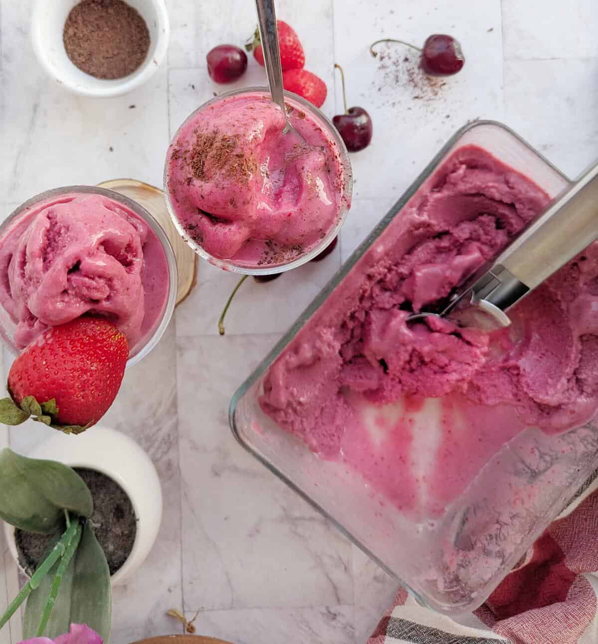 A bowl of plant-based ice cream with cherries and strawberries.
