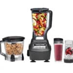 A blender and food processor with fruit and other ingredients in it.