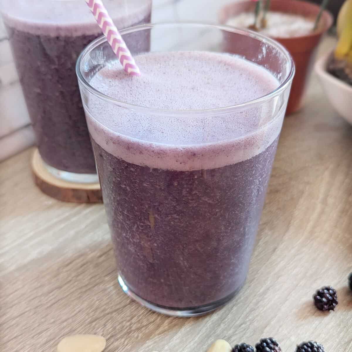 A glass of blackberry banana smoothie with almonds.