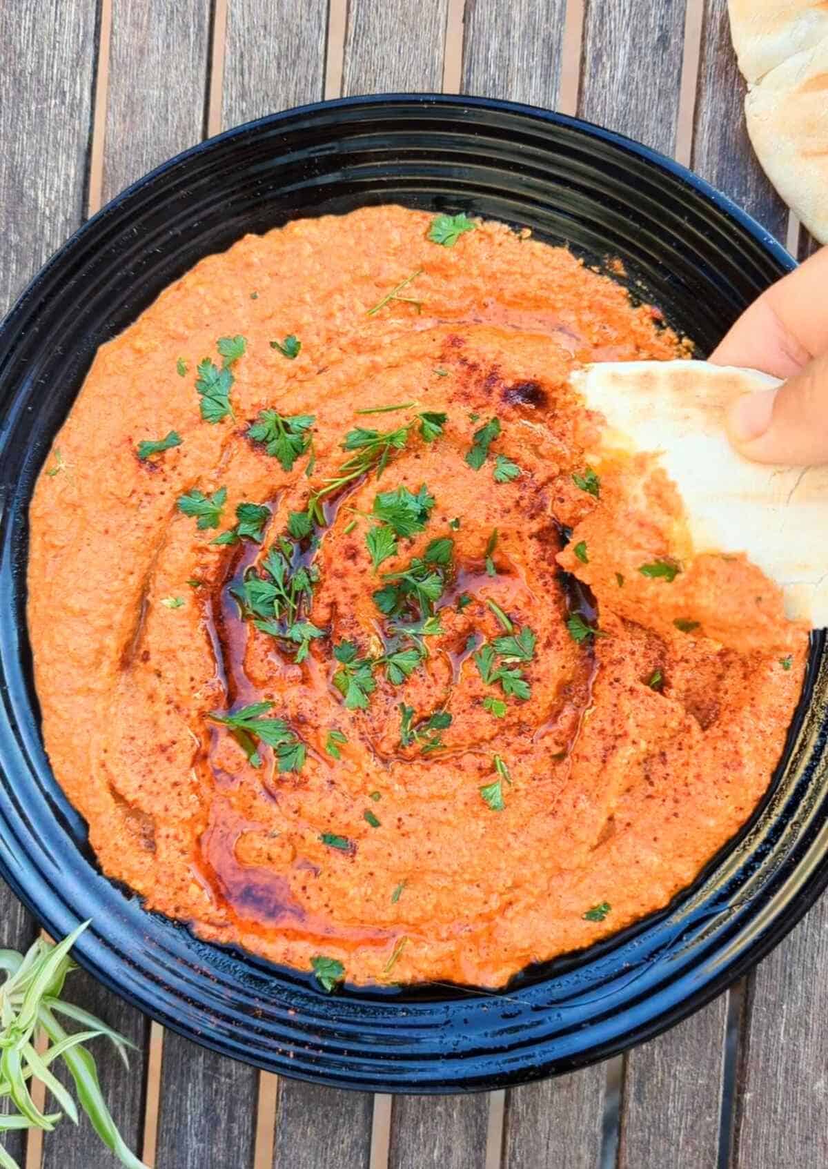 Pita bread dipped into unsweetended muhammara.