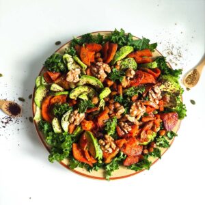 A plate of roasted squash, sweet potato, chickpeas, avocado, walnuts and kale.