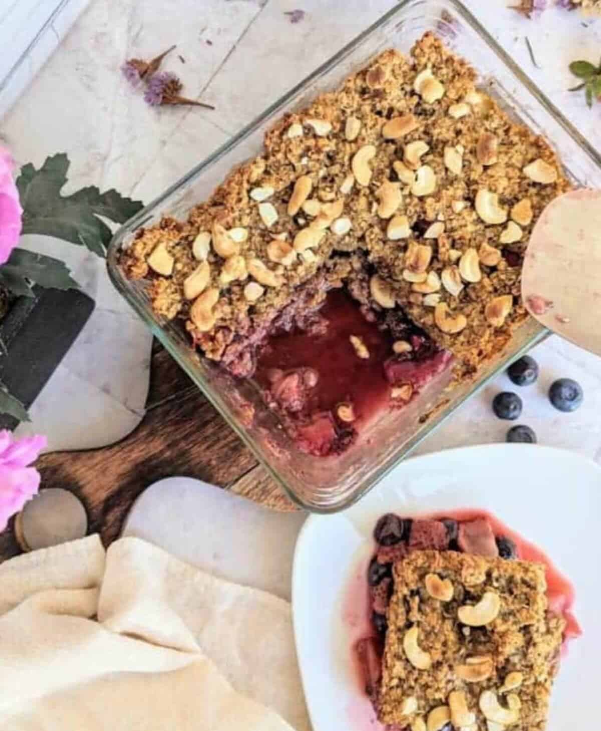 A dish displaying chia berry oat crumble with a plate showing a portion of it.