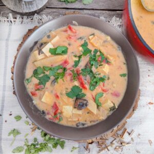 A bowl of creamy Thai soup with cilantro and bamboo shoots.