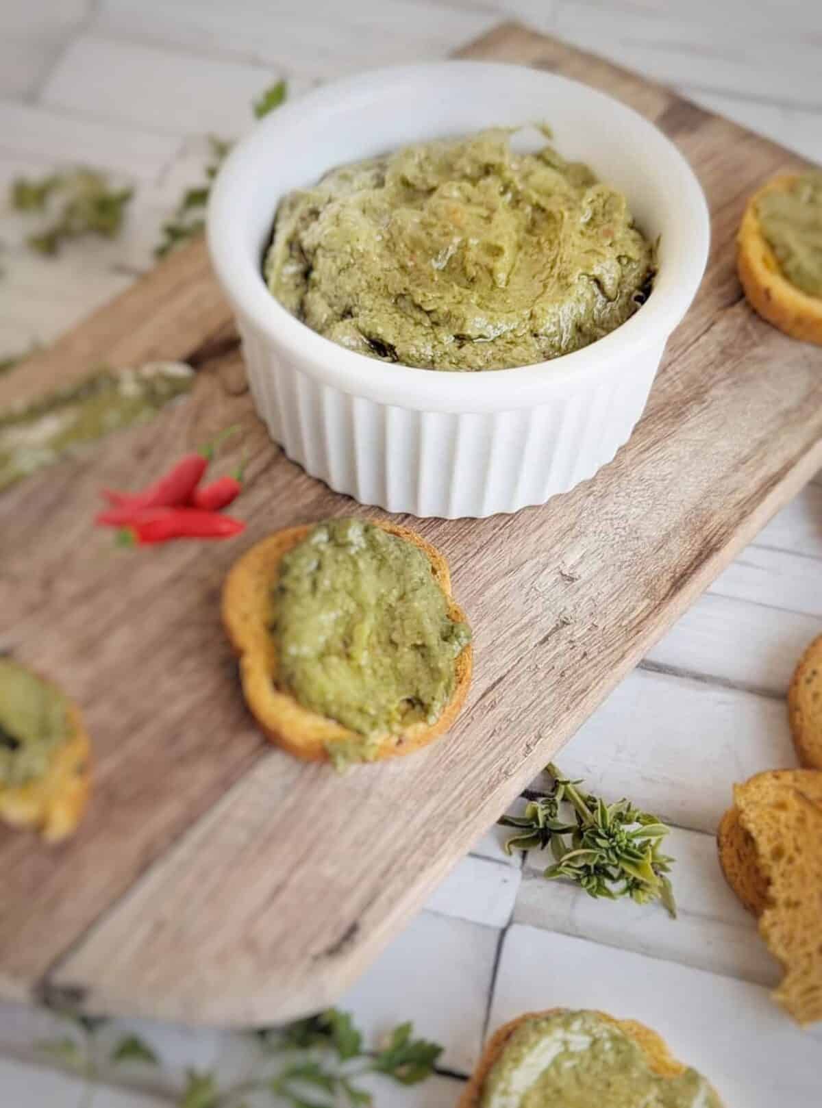 Vegan chili avocado with crispy toast around the pesto. A blurred out chili pepper in the background.