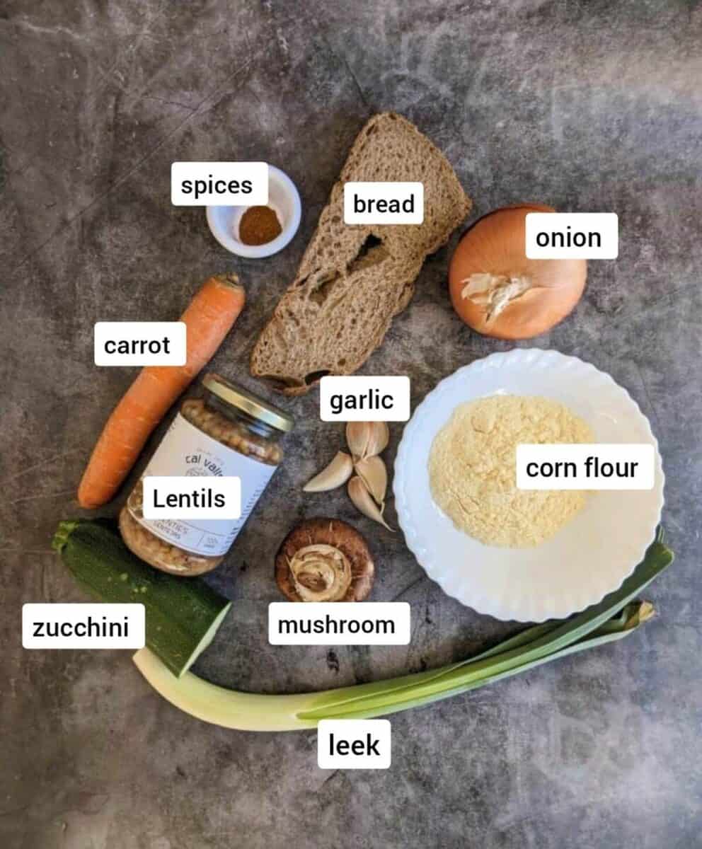 Vegan lentil balls ingredients featuring bread, carrots, onion, garlic, spices, and lentils on a dark background.