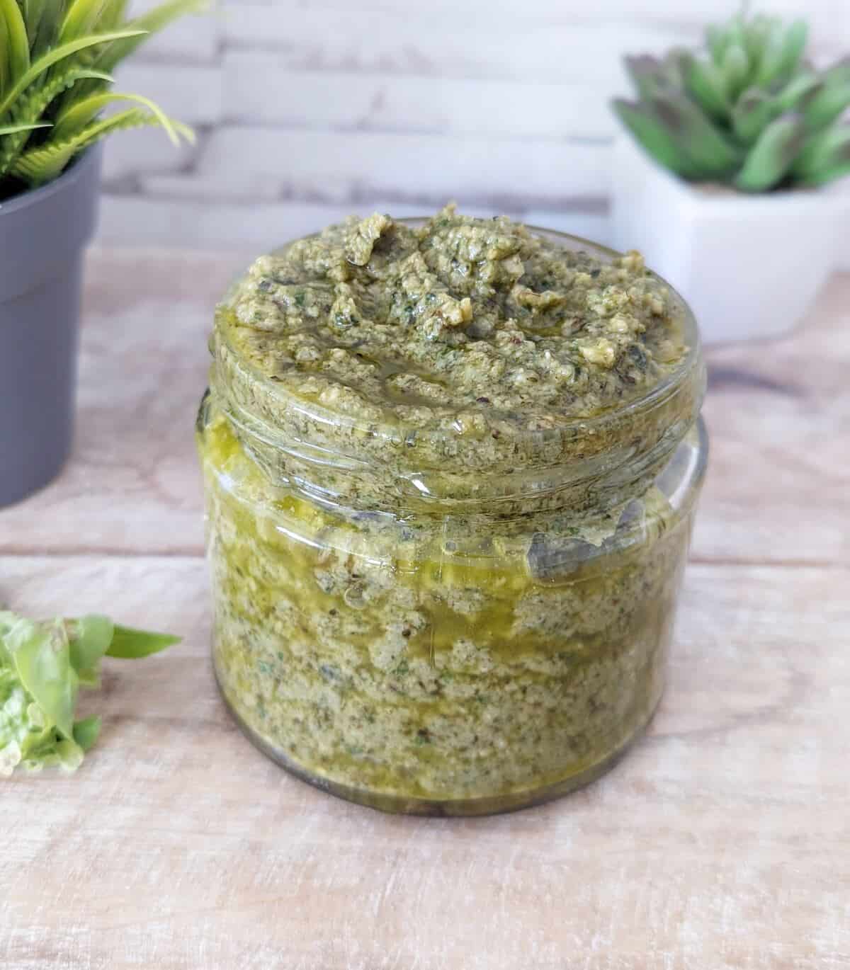 A jar of vegan black garlic pesto with ornaments faded in the background.