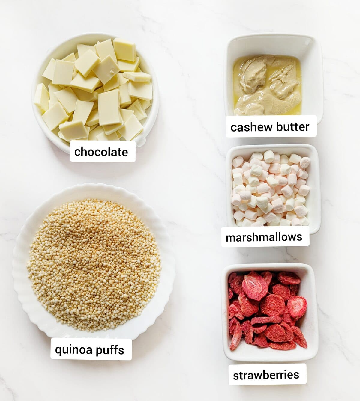Quinoa bite ingredients including chocolate, cashew butter, marshmallows, quinoa puffs, and strawberries.