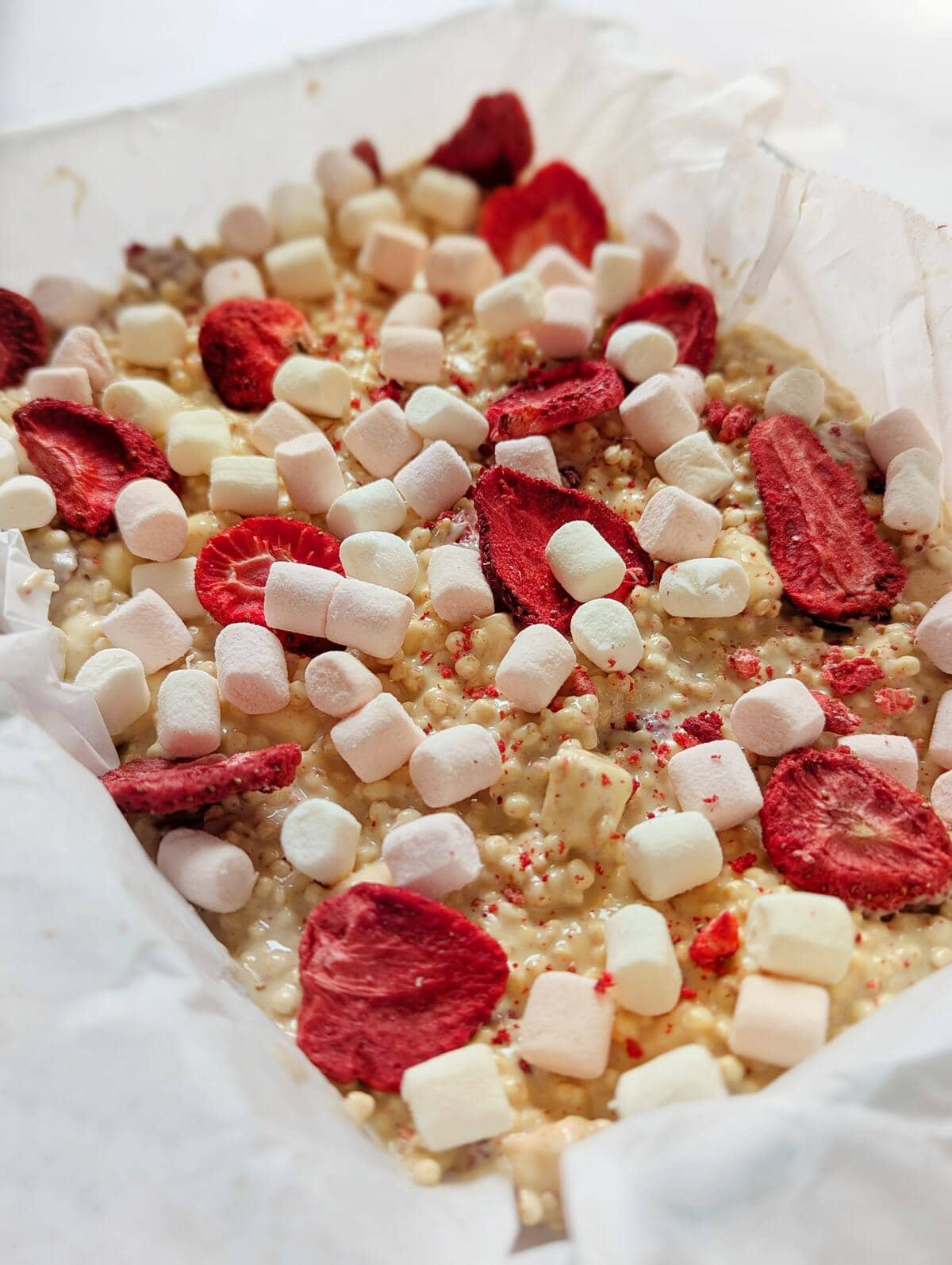 White chocolate quinoa dessert uncut decorated with marshmellows and dried strawberries.
