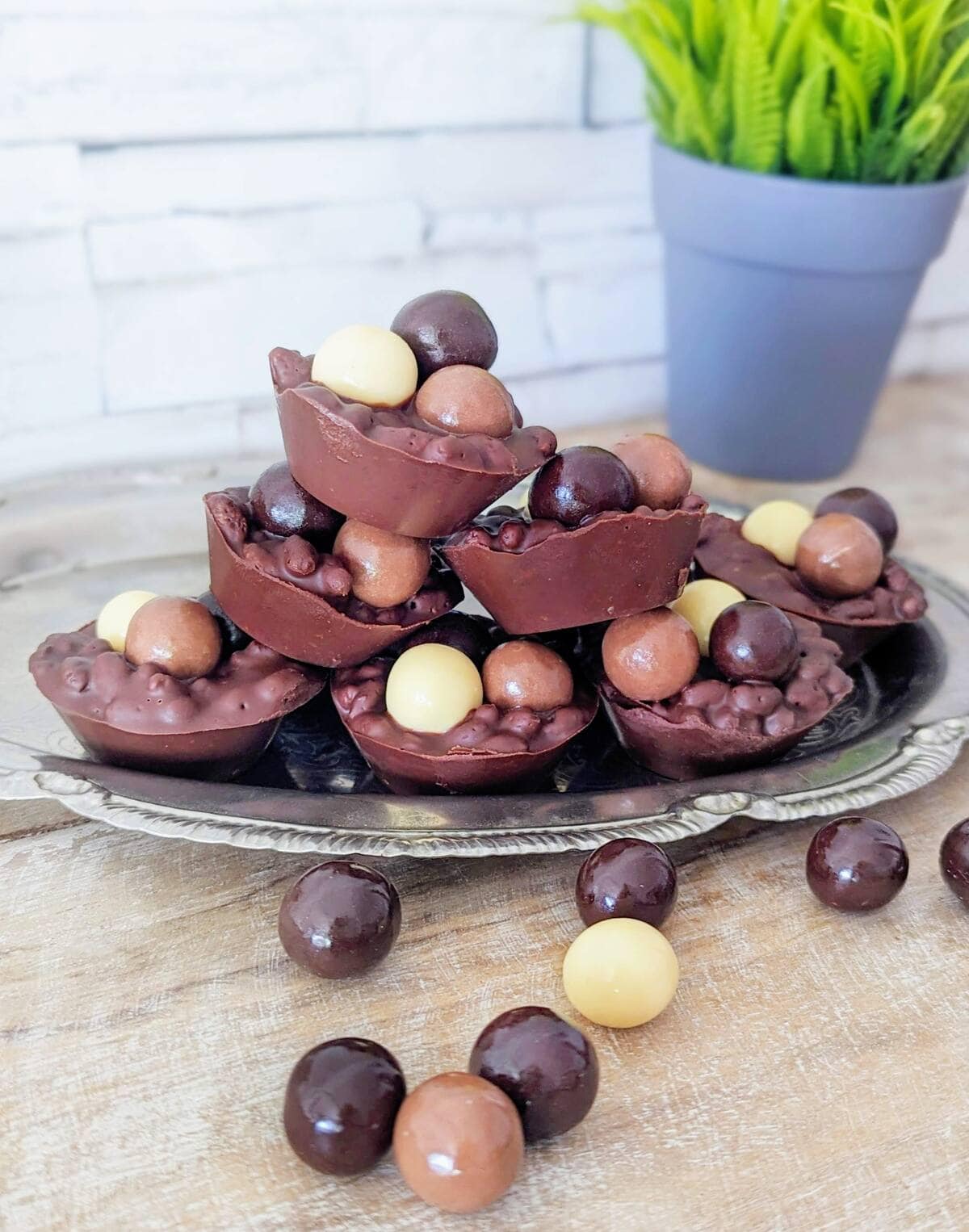 Chocolate puffed rice Easter cups on a tray, a faded plant is in the background.