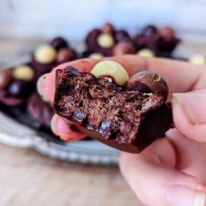 A hand holding a half eaten chocolate puffed rice Easter cup.