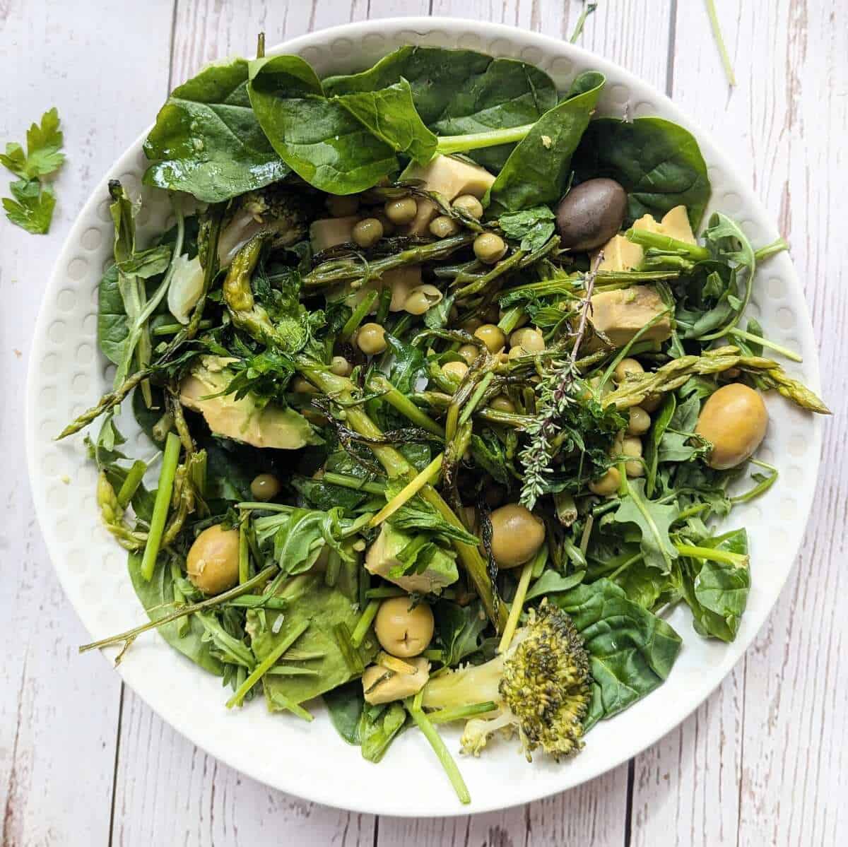 A plate of assorted fresh vegetables, asparaagus and herbs.