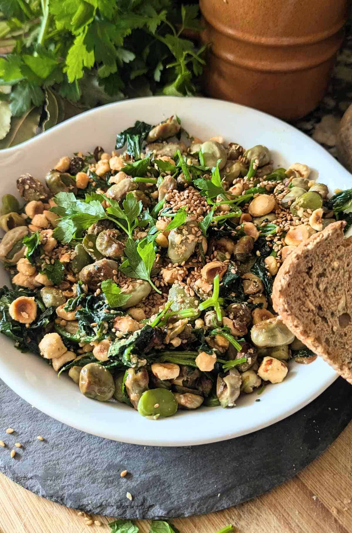 A plate of sautéed spinach and fava beans served with fresh bread on the side, and parsley at the back. A plate of sautéed spinach and fava beans served with fresh bread on the side.