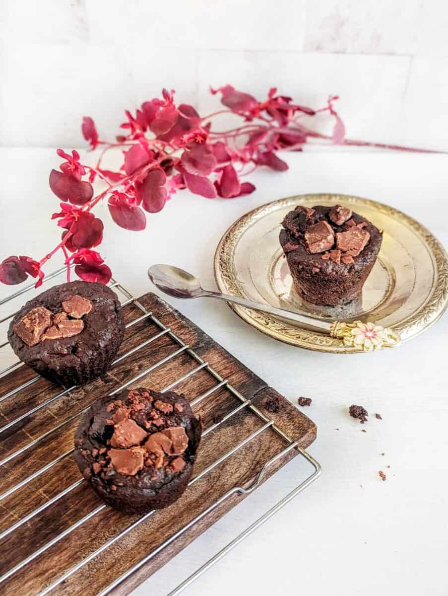 Vegan chocolate banana muffins with chunky topping on a cooling rack and plate.