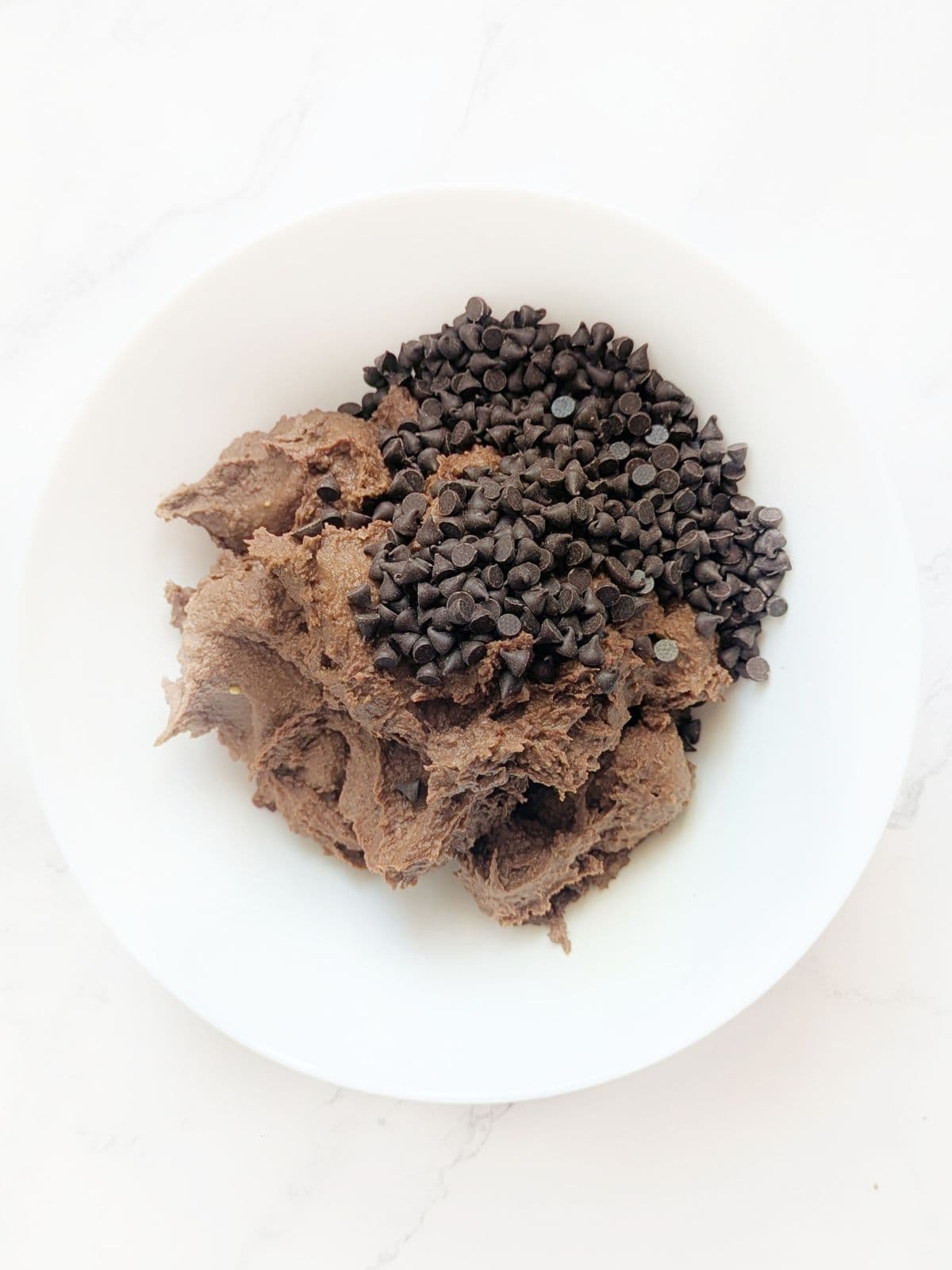 A bowl of gooey chocolate chickpea mixture with chocolate chips.
