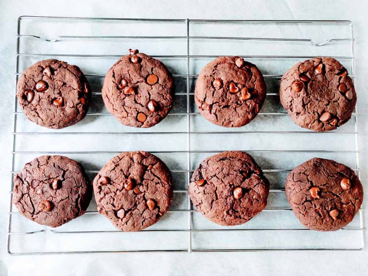 Freshly baked chocolate chickpea cookies cooling on a rack.
